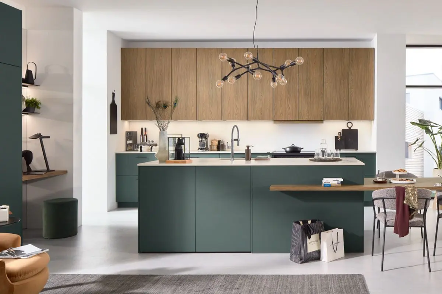 Eine moderne, grüne Küche mit einer Insel in der Mitte, mit hellbraunen Akzenten und schwarzen Elementen.